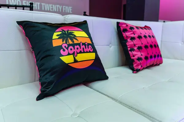 Sophie sunset logo pillow and palm print pillow on a white sofa