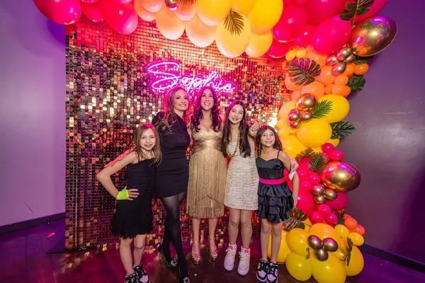 Guests at the Sophie neon sequin backdrop with tropical balloon arch