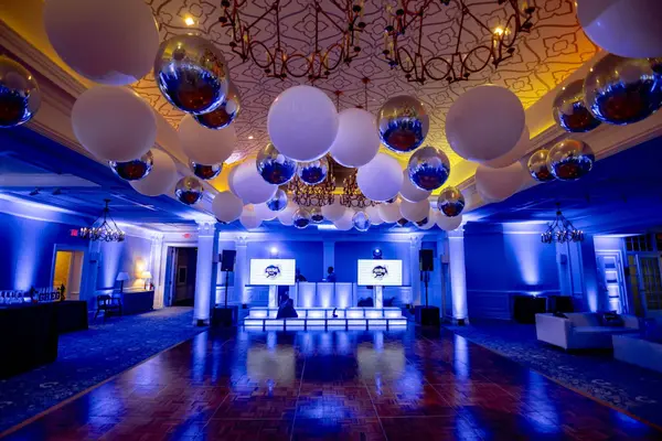 Ballroom with balloon ceiling, DJ screens and blue uplighting