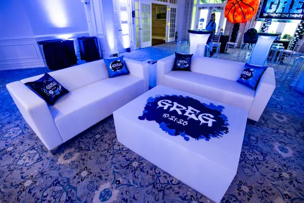 White lounge with Greg logo table and pillows