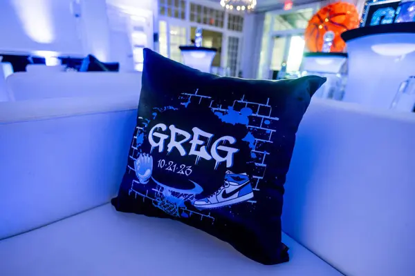 Black Greg logo pillow with sneaker and brick wall graphic
