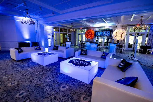White lounge with lit Greg logo tables at Greg's Bar Mitzvah