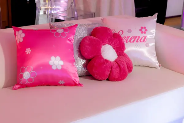 Pink daisy, sequin and Serena pillows on a lounge sofa