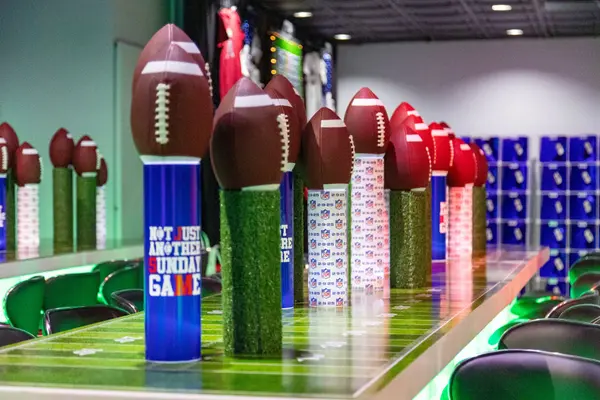 Football centerpieces on turf and logo-wrapped columns along the high-top tables