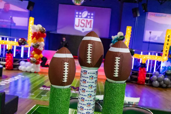 Three football centerpieces with the JSM logo projected behind