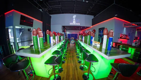 Green-lit high-top tables with football centerpieces at Jeremy's Bar Mitzvah