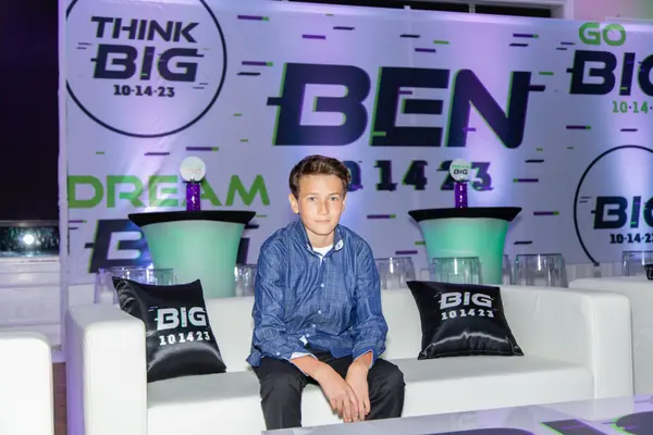 The honoree on the Ben's Bar Mitzvah lounge sofa with logo pillows
