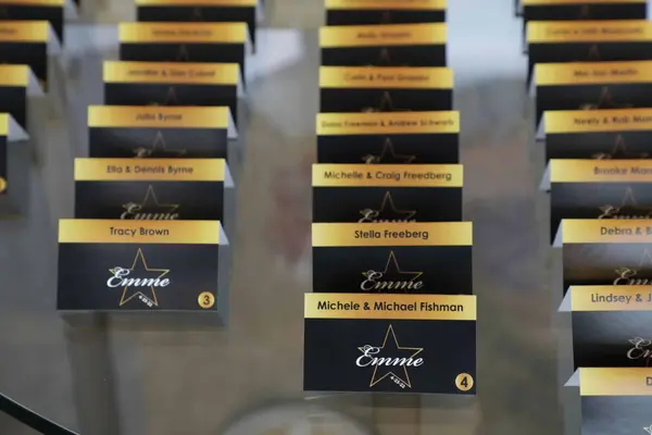 Black and gold Emme star logo escort cards on a mirrored table