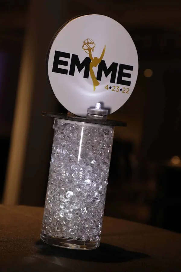 Emme logo topper on a lit crystal-filled cylinder centerpiece