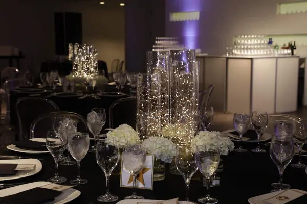 Fairy light cylinder centerpiece with white hydrangea on a black table