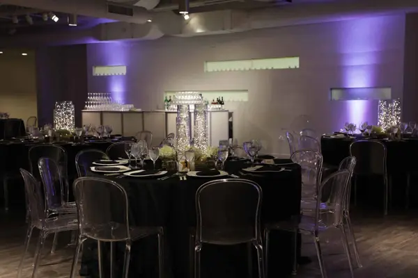 Black linen tables with clear chairs and fairy light centerpieces