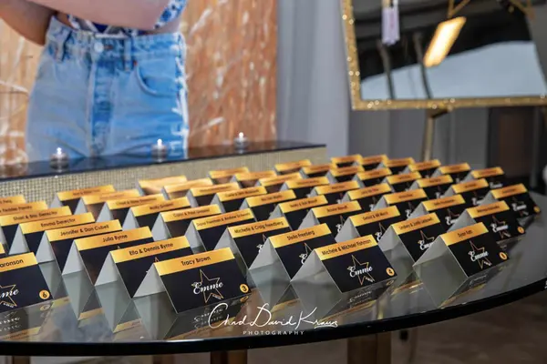 Close-up of gold and black Emme escort cards on the mirrored table