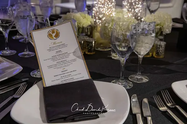 Custom gold-bordered menu card on a black napkin place setting