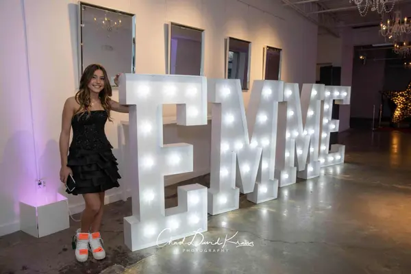 The honoree beside giant EMME marquee letters at Emme's Bat Mitzvah