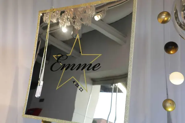 Gold-framed Emme logo sign-in mirror with hanging balloons