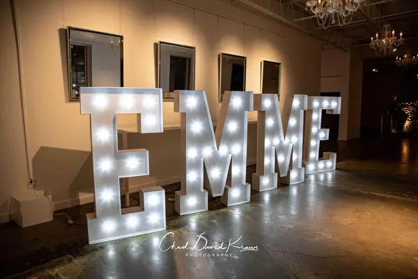 Giant lit EMME marquee letters along a mirrored wall