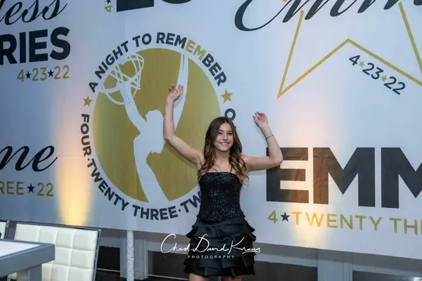 The honoree in front of the printed Emme logo wall