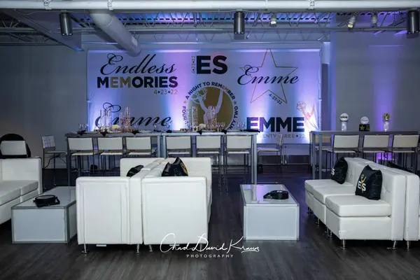 White lounge with logo pillows and the Emme backdrop wall