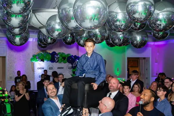 The honoree lifted in a chair under balloons at Ben's Bar Mitzvah