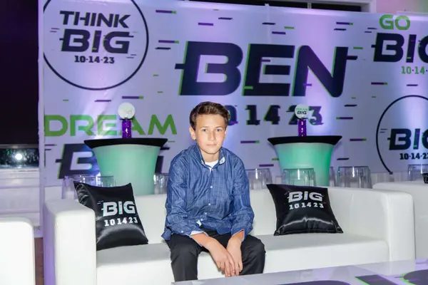 The honoree on the lounge sofa in front of the Ben backdrop