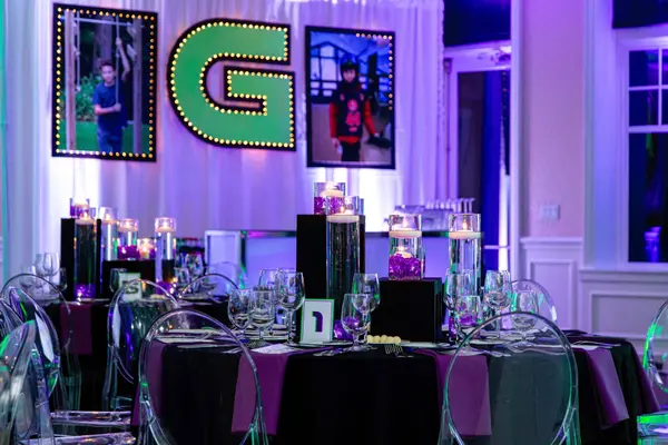 Marquee G and photo displays behind purple tables at Ben's Bar Mitzvah