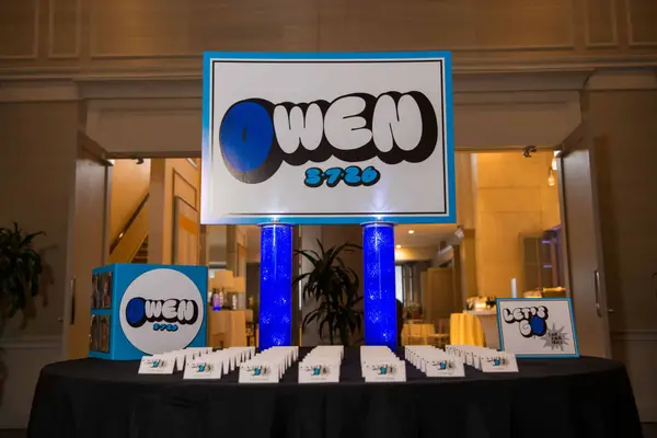 Owen's Bar Mitzvah logo sign over escort card table with blue columns