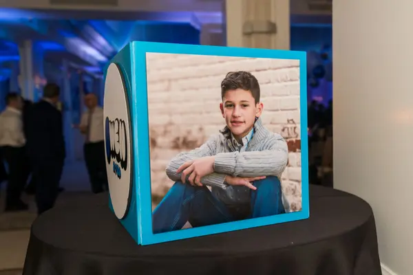 Owen's Bar Mitzvah photo cube with logo on a cocktail table