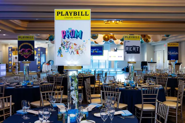 Emily's Bat Mitzvah Playbill centerpieces on navy tables with balloon ceiling