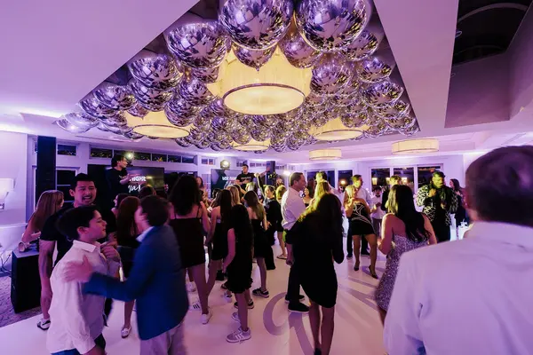 Ella's Bat Mitzvah guests dancing under the silver orb balloon ceiling